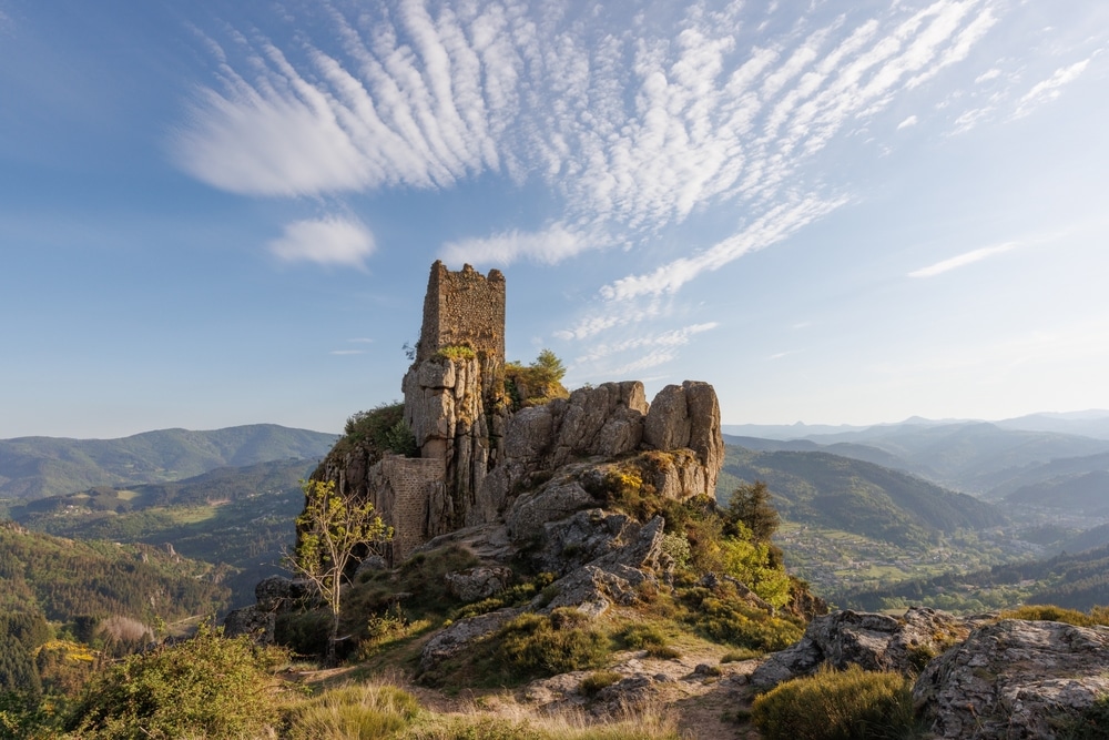 bijzondere rotsformatie en overblijfselen van het kasteel van Rochebonne in de Ardéche met op de achtergrond een schitterend uitzicht op het heuvelachtige gebied op een zonnige dag