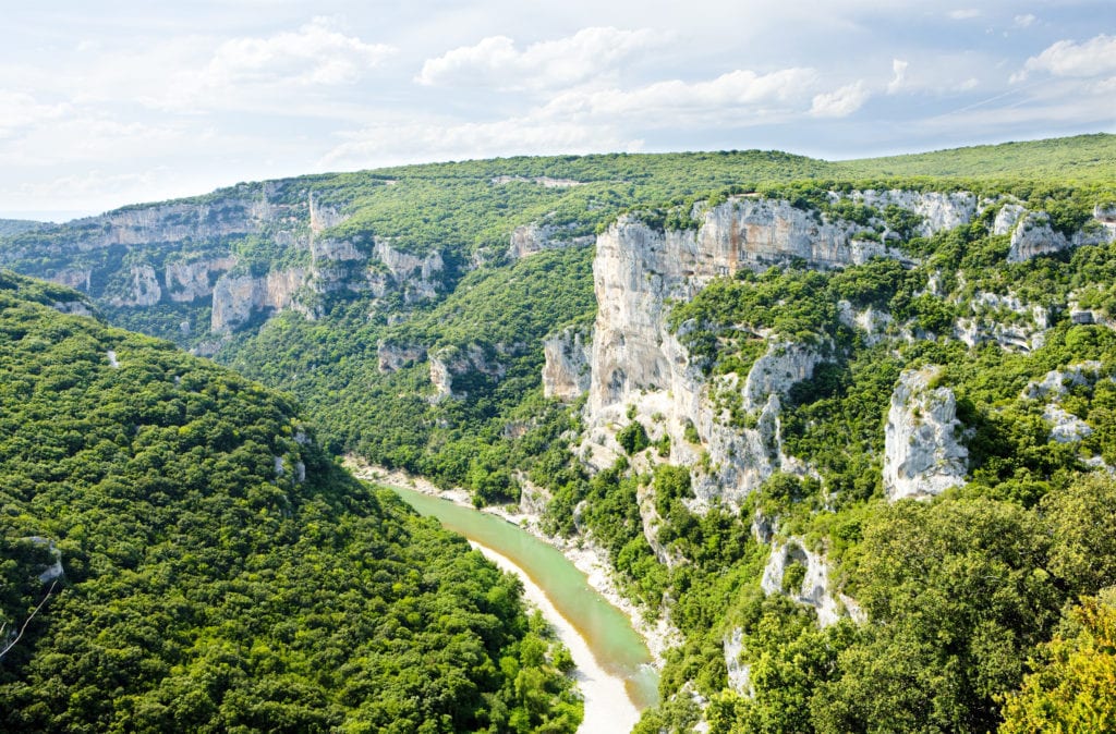 luchtfoto van een rivierkloof met steile, groen begroeide kliffen in de Ardèche