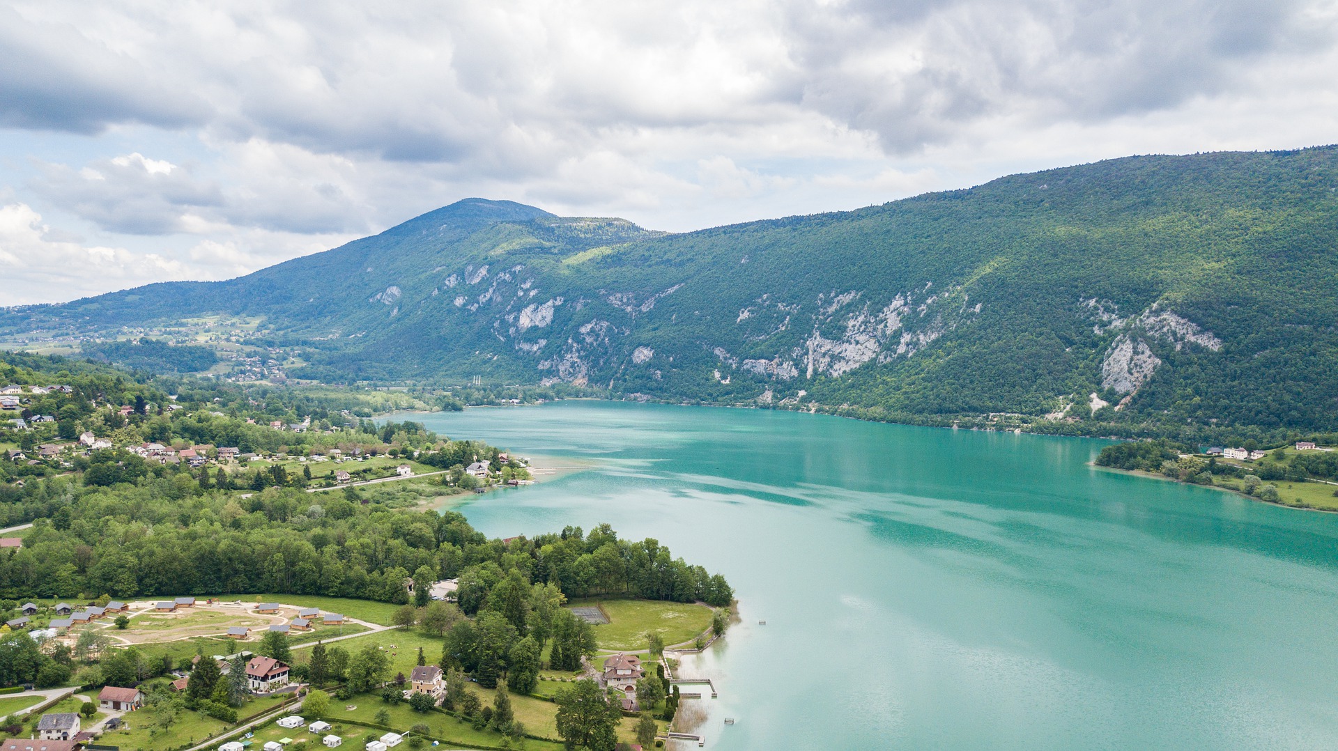 lac d'aiguebelette helderblauw meer omgeven door bergen, platteland en bossen