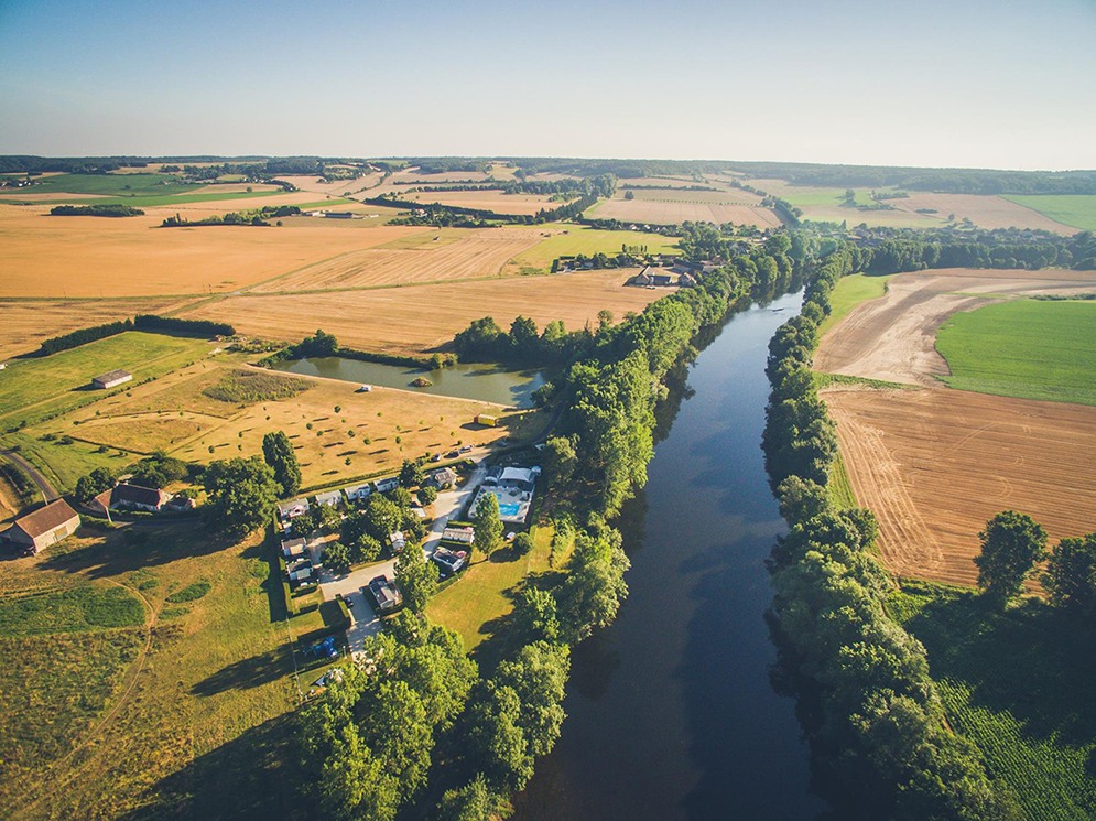 rivier die door het platteland loopt met aan de linkeroever een camping met zwembad gelegen