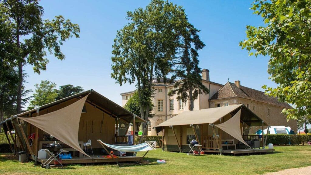 twee safaritenten met een deels overdekte veranda op Camping Château de l'Eperviere en op de achtergrond het kasteel