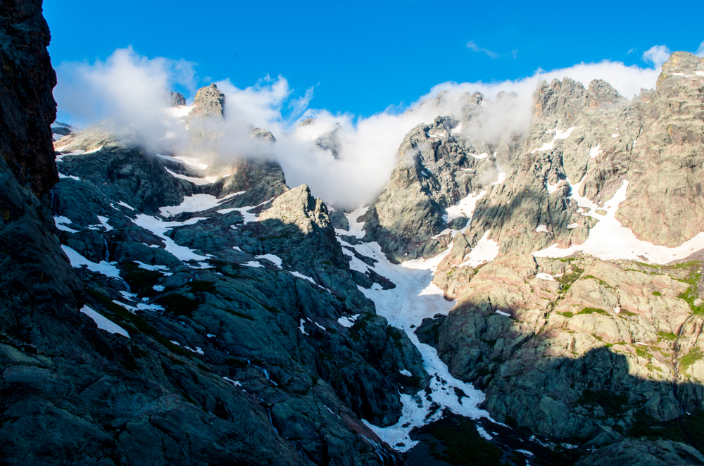 rotsen met sneeuwresten en laaghangende wolken in het Parc Naturel régional de Corse op Corsica