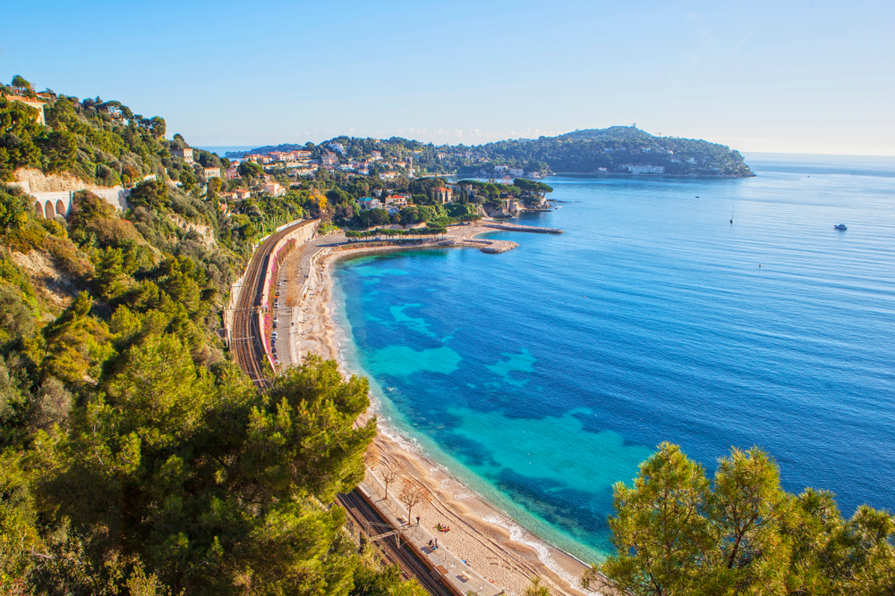 foto van een azuurblauwe zee in een uitgestrekte baai met een lang zandstrand in Antibes