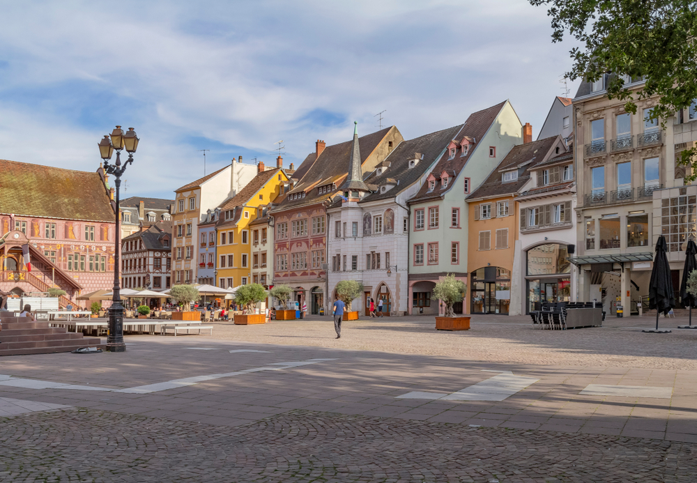 gekleurde huizen, winkels en een terras aan het Place de la Réunion in Mulhouse