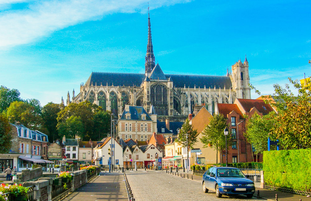 straat met huizen en een auto en op de achtergrond een kathedraal in Amiens