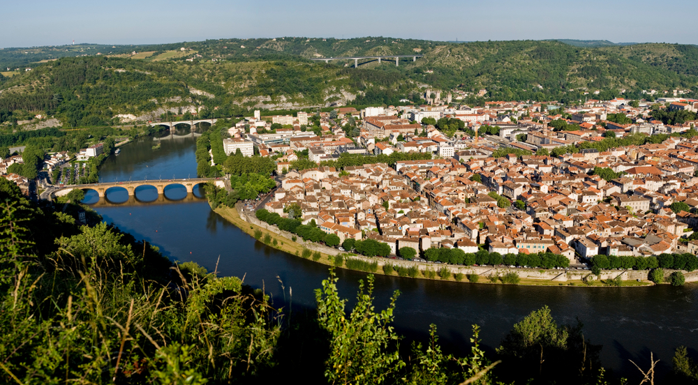 De stad Cahors gezien vanuit vogelperspectief. Rondom de stad roomt de rivier de Lot en zie je meerdere bruggen over de rivier naar de stad.