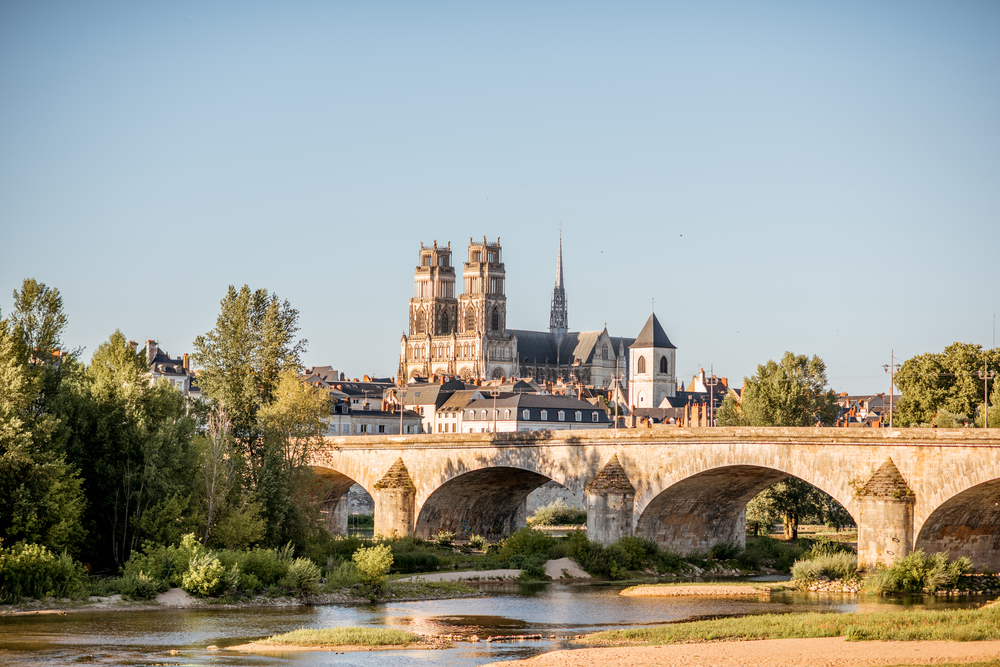 brug over de - bijna droog liggende - rivier de Loire met daarachter de stad Orléans met zijn kathedraal en andere historische gebouwen op een zonnige namiddag