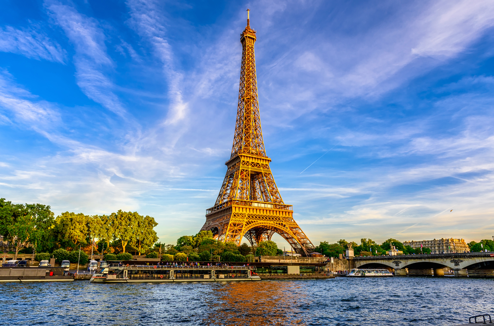De Eiffeltoren gezien vanaf de Seine op een zonnige namiddag. Je kunt aan de goudgele kleur van de Eiffeltoren zien dat het kort voor zonsondergang is. 