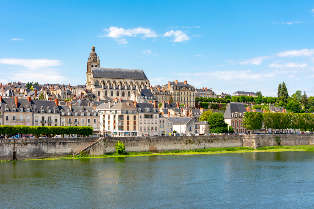 Groot kasteel met rode kleine torentjes gelegen aan rivier de Loire.
