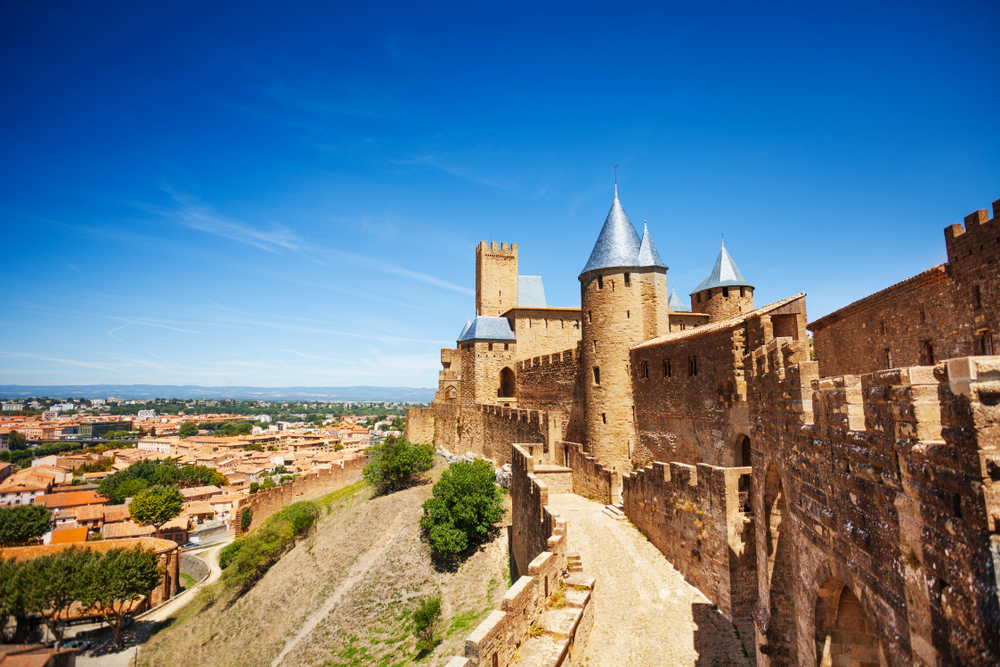 zijkant van het kasteel van Carcassonne met op de andere helft van de foto het lager gelegen dorp op een zonnige dag