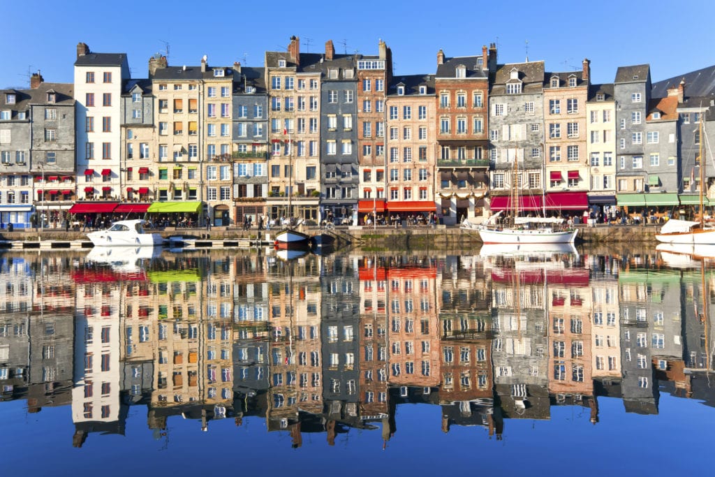 De schilderachtige haven van Honfleur met vissersbootjes in het water en gekleurde huisjes langs de gevel. 