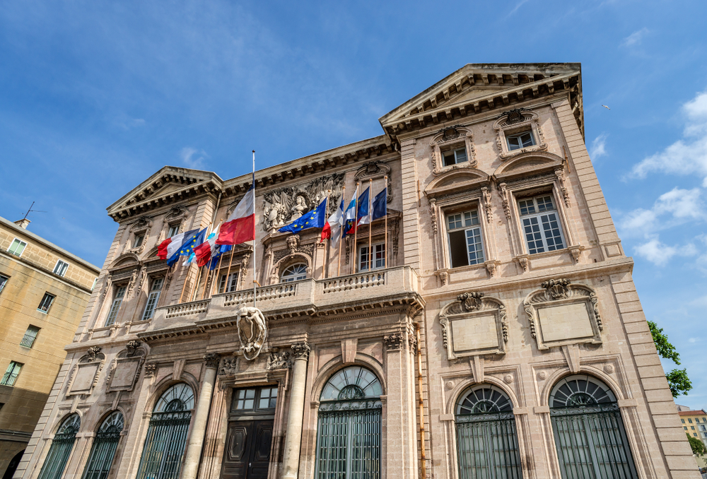 Zandkleurig historisch gebouw met Franse en Europese vlaggen. 