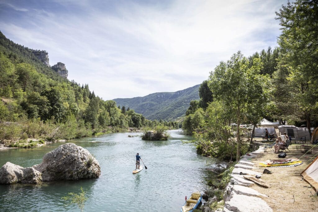 iemand op een sup board op het water in de Gorges du Tarn, naast een camping