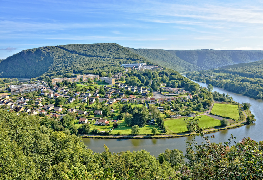 Groene bergen en bossen met de daar doorheen lopende rivier en verschillende huizen en gebouwen.