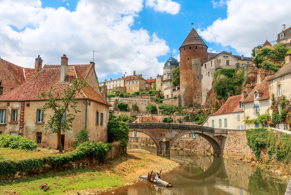 een brug over een rivier en huizen en een toren aan de zijkant in Semur-en-Auxois