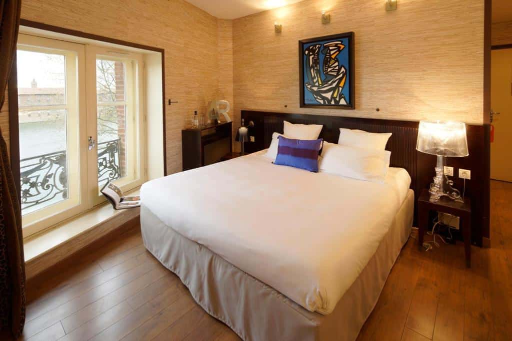hotelkamer met een opgemaakt tweepersoonsbed en uitzicht op het water in een boetiekhotel in Toulouse