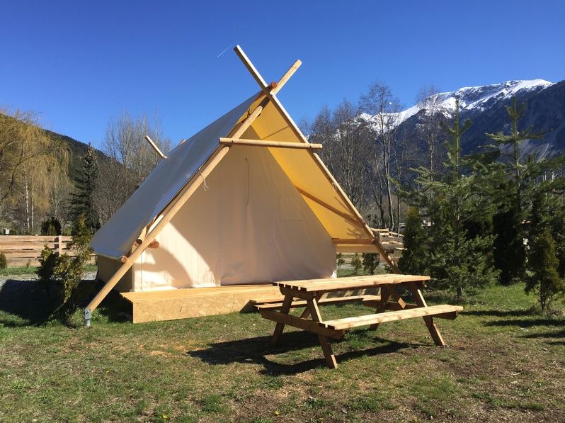 canvastent op Flower Camping Le Montana in de Franse Alpen. De tent is dicht en voor de tent staat een houten picknicktafel.
