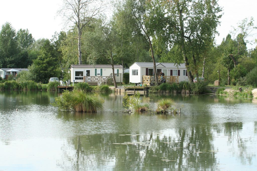 witte stacaravans gelegen aan een vijver op Camping Les Puits Tournants 