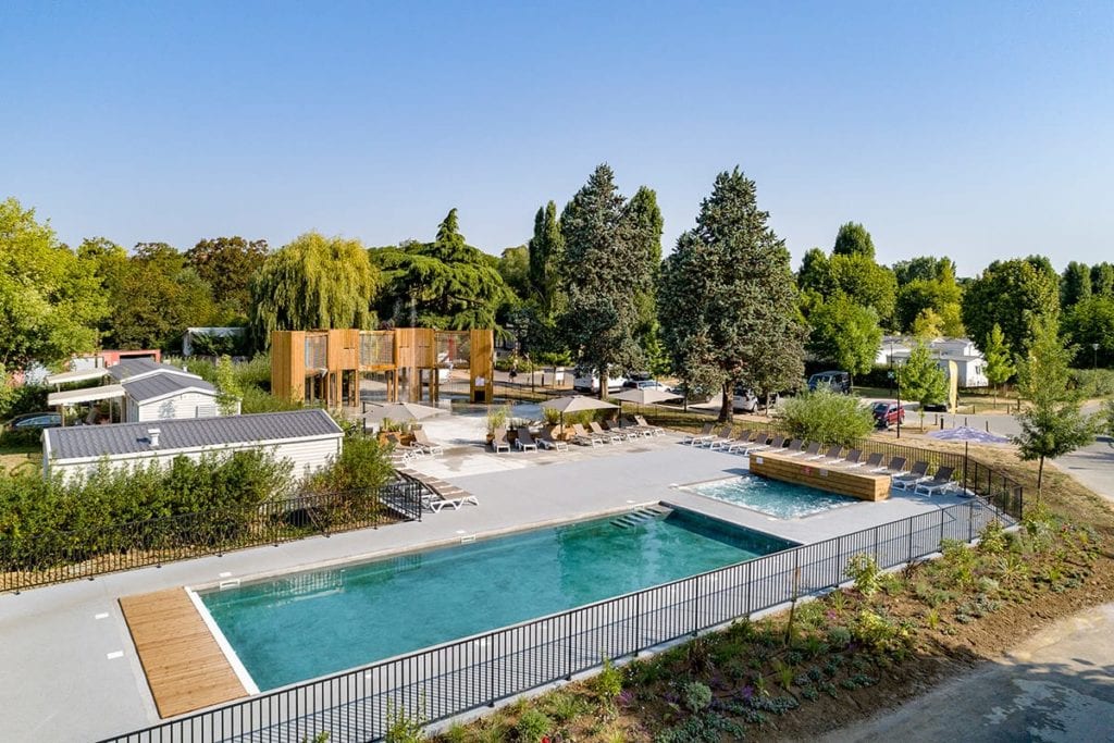 foto van een modern en strak uitziend zwembad op vakantiepark Paris Maisons-Laffitte. Het zwembad is leeg en er staan strandstoelen en er is een jaczzi
