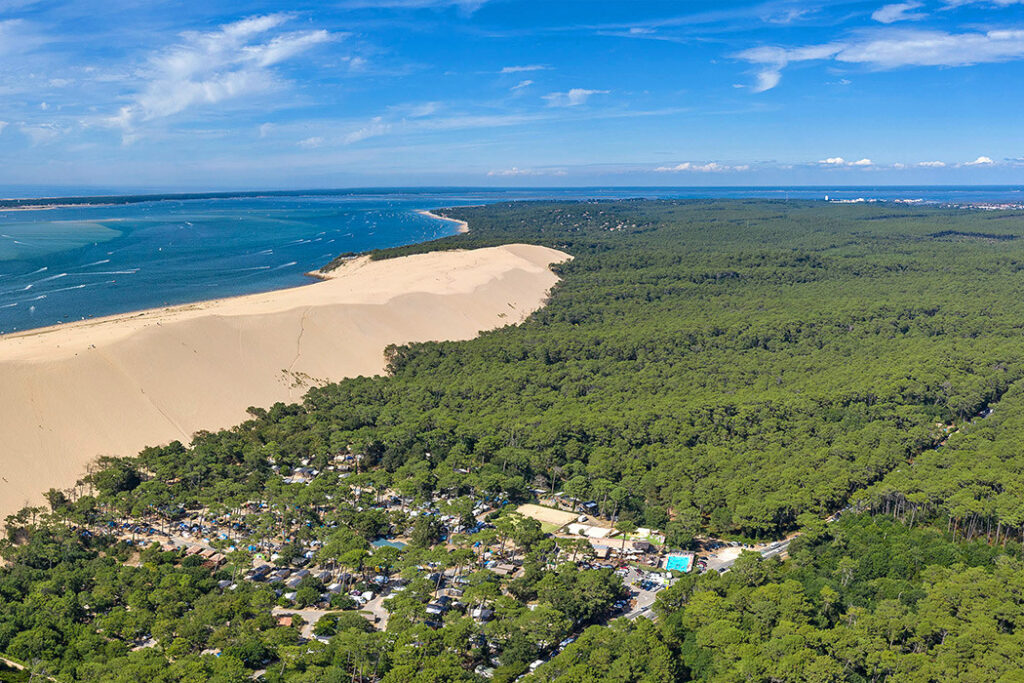 Bovenaanzicht van Camping La Forêt du Pilat met rondom een bos, de zandduin en de zee.