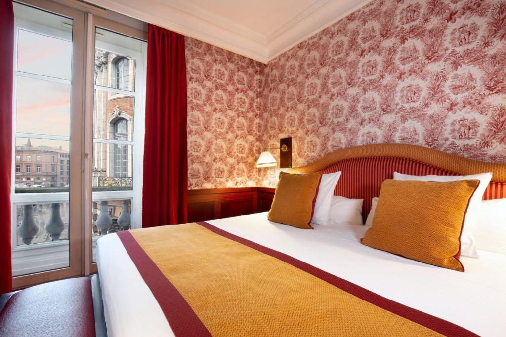 kamer met rood-wit behang, een tweepersoonsbed en straatuitzicht in Grand Hotel de l'Opera in Toulouse