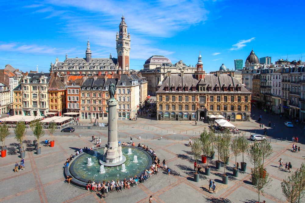 het centrale plein Place du Général-de-Gaulle in Lille. Er zitten veel mensen op de ronde bank rondom de fontein