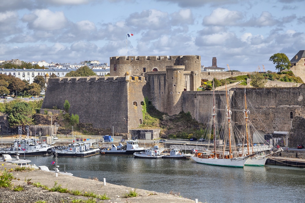 Jachthaven met boten grenzen aan een groot stenen fort met Franse vlag in Brest.