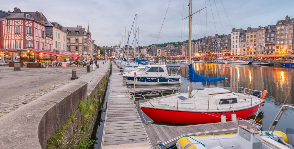 Aangemeerde vissersboten op het water van Fécamp met omliggende vakwerkhuizen.