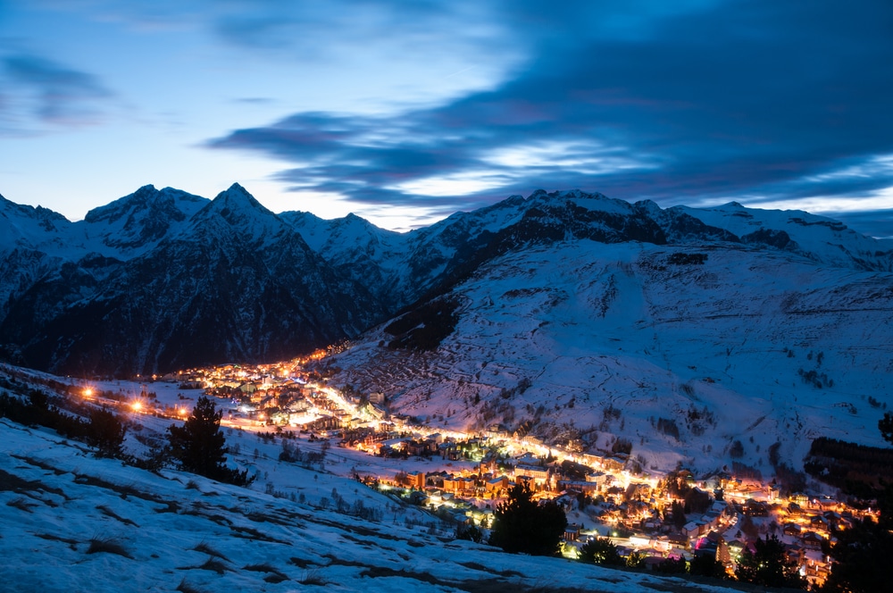 Het verlichte wintersportdorp Les Deux Alpes van bovenaf gezien in de avond.