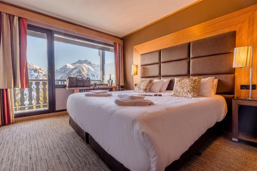 Hotelkamer met tweepersoonsbed en uitzicht op de bergen in het moderne Madame Vacances Hôtel Ibiza hotel in het skigebied Les Deux Alpes in Frankrijk.