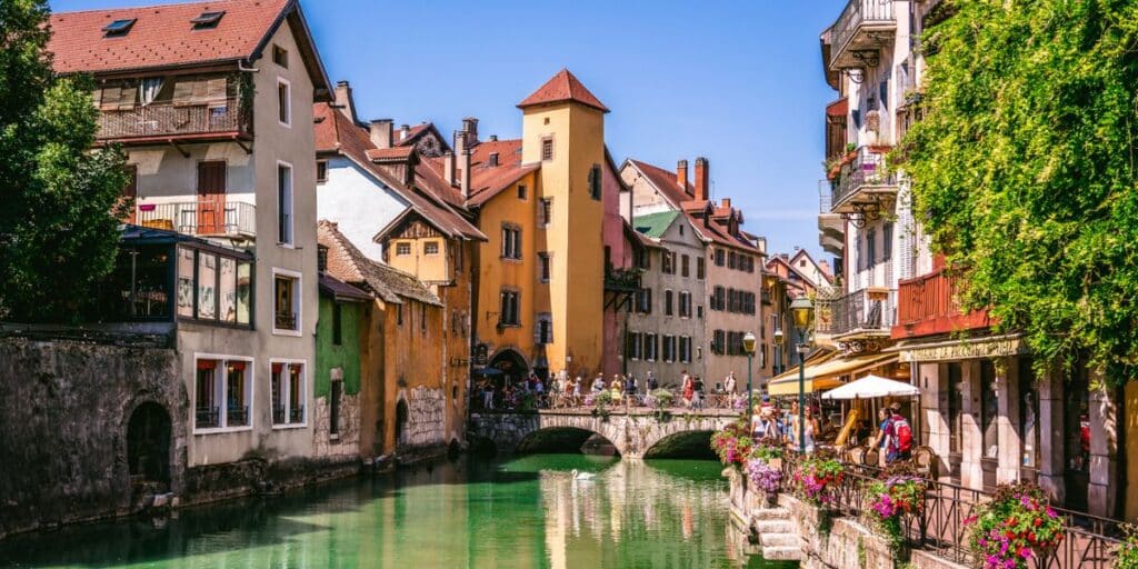 toeristen op een zonnige dag rondom een grachtje in Annecy