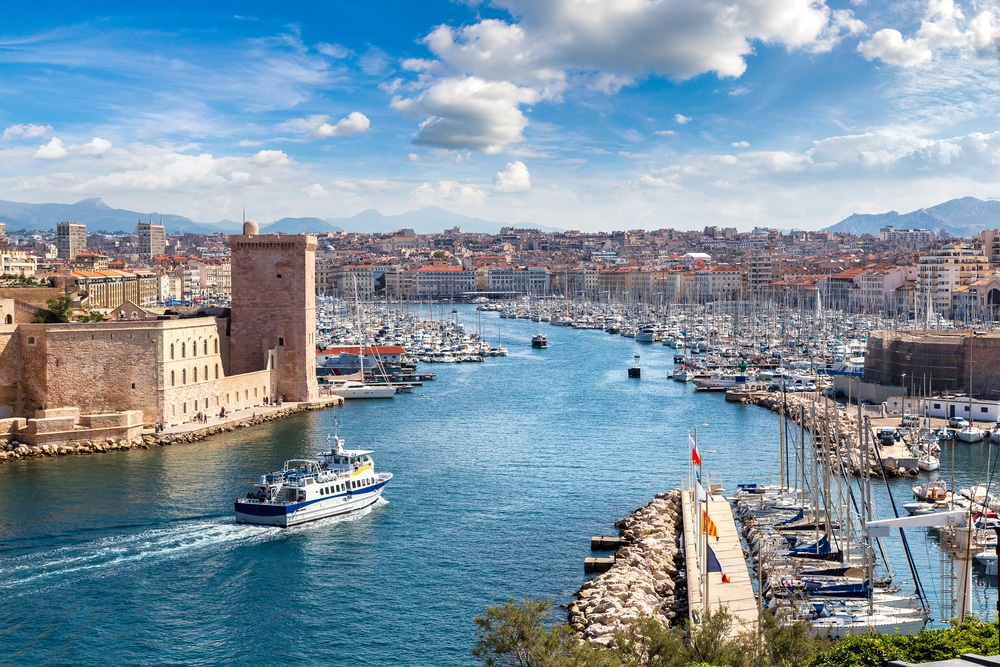 Foto van de wateren en de haven van Marseille met ontzettend veel bootjes en omringd door gebouwen.