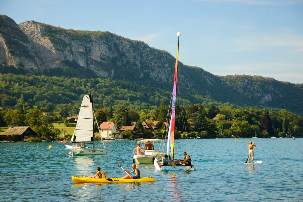 toeristen in een kano, op een sup en in in bootjes op een zonnige dag op het meer van Annecy