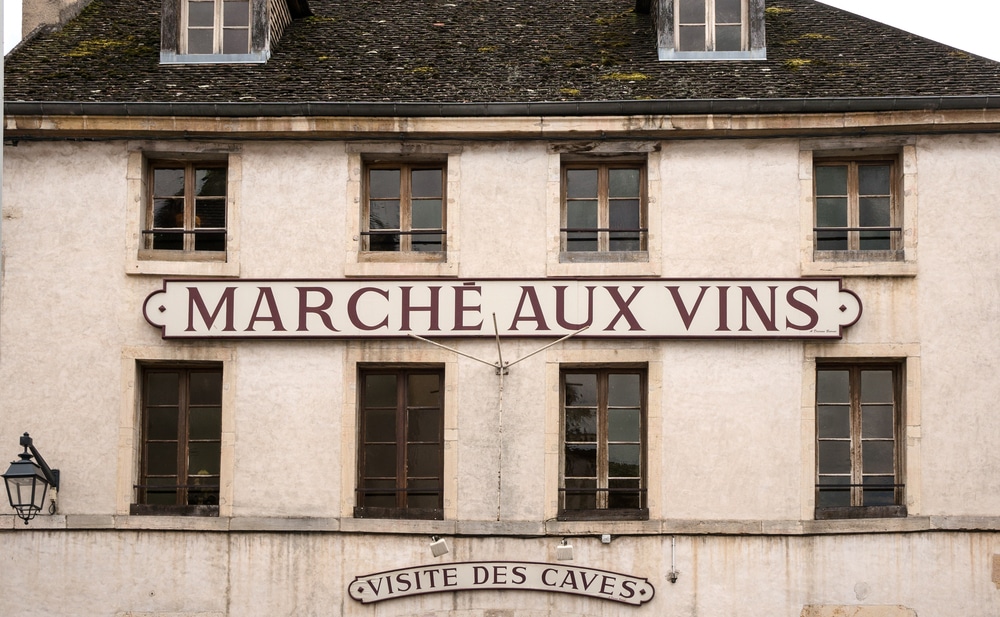 De gevel van en gebouw met daarop een bord met de tekst "Marché aux Vis". Onder hangt nog een kleiner bordje met de tekst "Visite des caves"