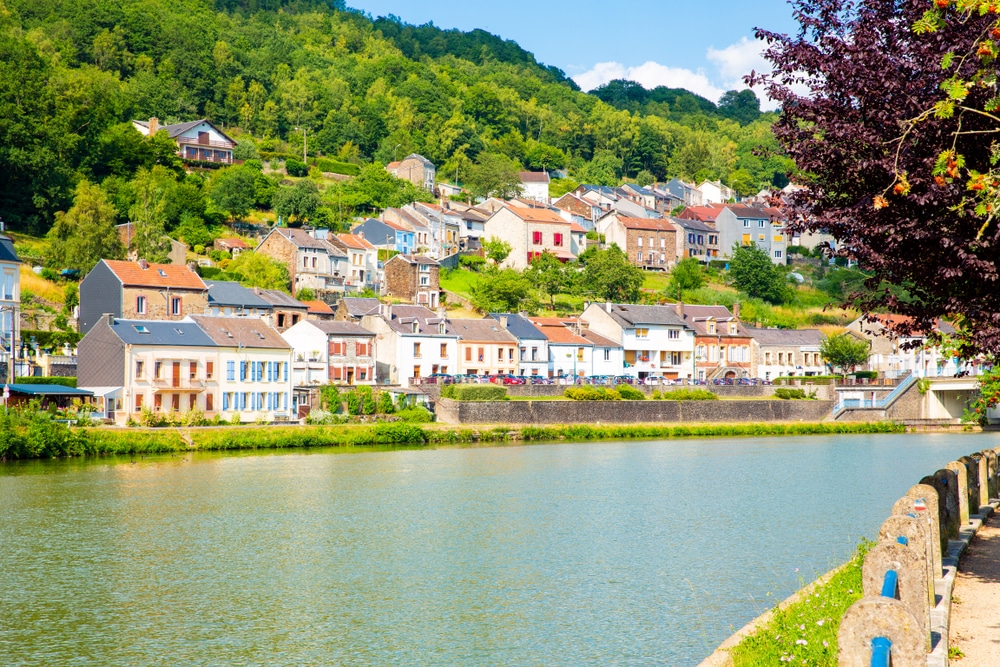 Stadje met kleurrijke huisjes gelegen langs de rivier en omringd door groene bomen.