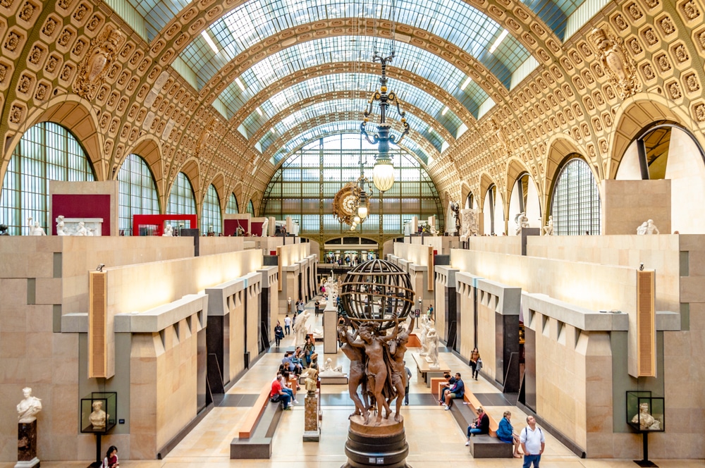binnenkant van het museum Musée d'Orsay in Parijs met beeld in het midden waar mensen rondlopen en duidelijk te zien is dat het is gevestigd in een oud treinstation