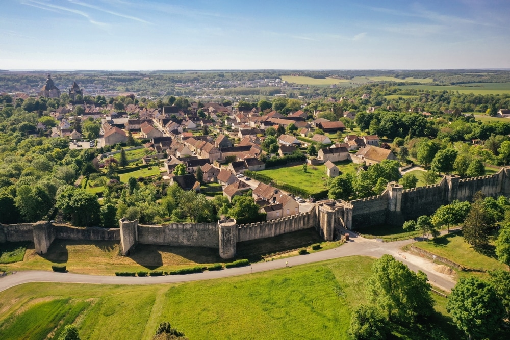 Uitzicht op de huizen van het middeleeuwse dorpje Provins omringd door veel groene bomen en een stenen stadsmuur.