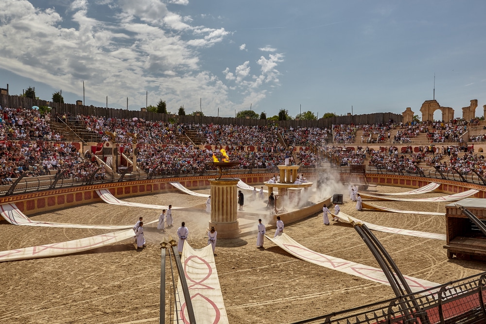 Arena met mensen op de tribune die kijken naar een middeleeuwse show die wordt gegeven in het midden.