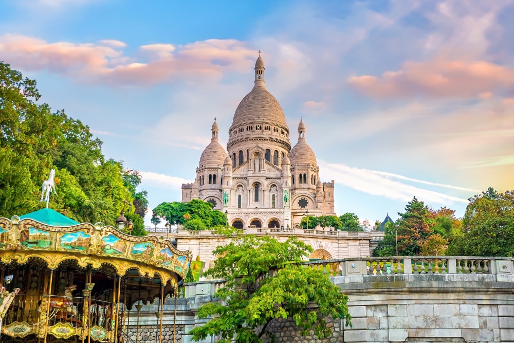 de Basilique du Sacré-Cœur omringd door bomen en de daarvoor gelegen draaimolen en stenen trappen zonder mensen