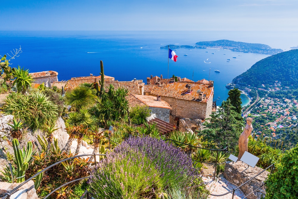 Planten en oranje daken van het dorpje Èze dat uitzicht biedt op de Middellandse Zee en de omliggende dorpen en heuvels.