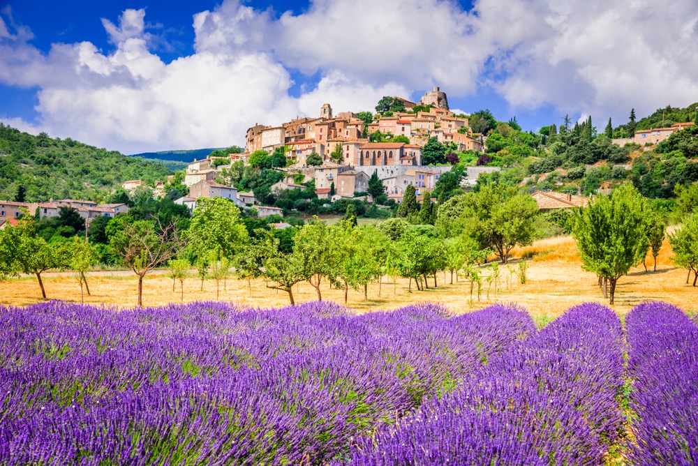 Het dorp Simiane-la-Rotonde gelegen in groene heuvels en omringd door paarse lavendelvelden en wijngaarden.