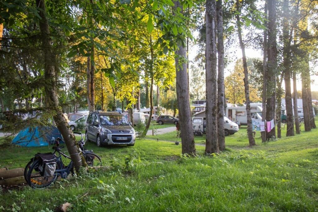 fietsen, auto's, campers en tenten tussen de bomen op Camping de I'ile