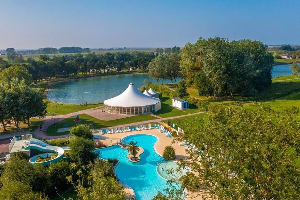 luchtfoto van Camping Le Fanal met daarop het zwembad, de waterglijbanen, een meer en een soort witte circustent