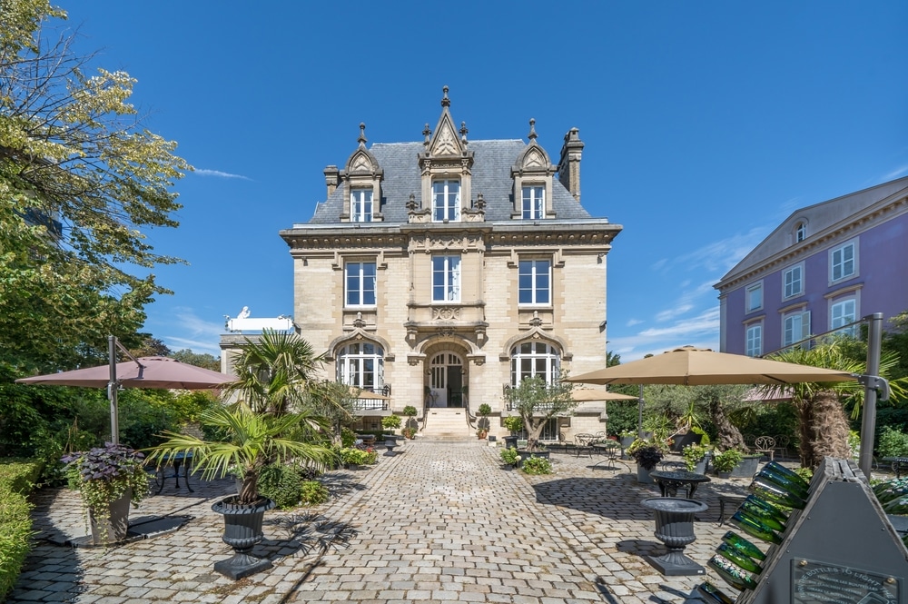 Champagnehuis gelegen op aan een stenen terras met zitplekken, parasols en planten aan de Avenue de Champagne in Épernay.