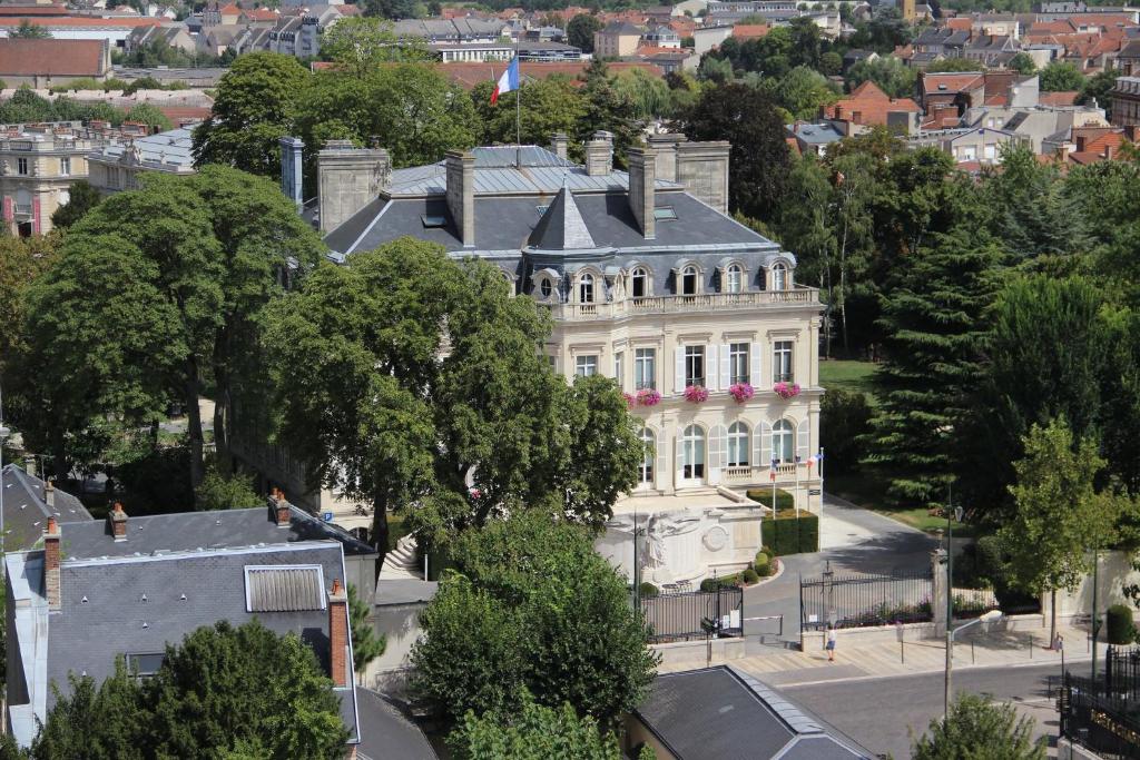 Wit gebouw met grijze daken gelegen in de stad Épernay en omringd door bomen en andere gebouwen.