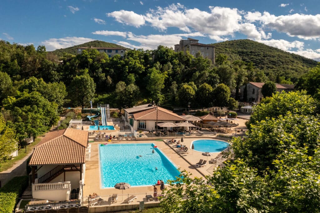 de zwembaden op camping RCN la Bastide en Ardèche met daarachter twee met groen begroeide bergen