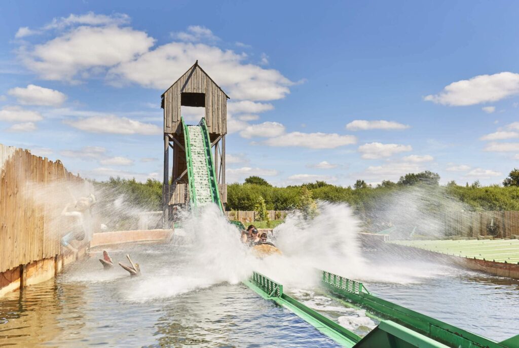 gezin dat in een karretje in de vorm van een boomstam een waterattractie afroetsjt in pretpark Kingoland in Frankrijk