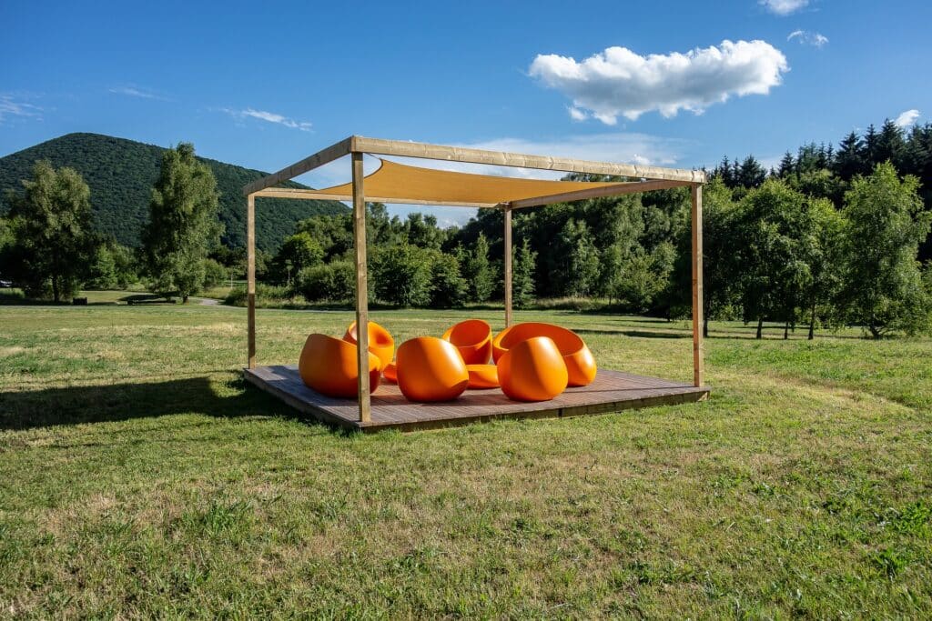 ronde, oranje plastic stoelen op een overdekt vonder in het gras in themapark Vulciana