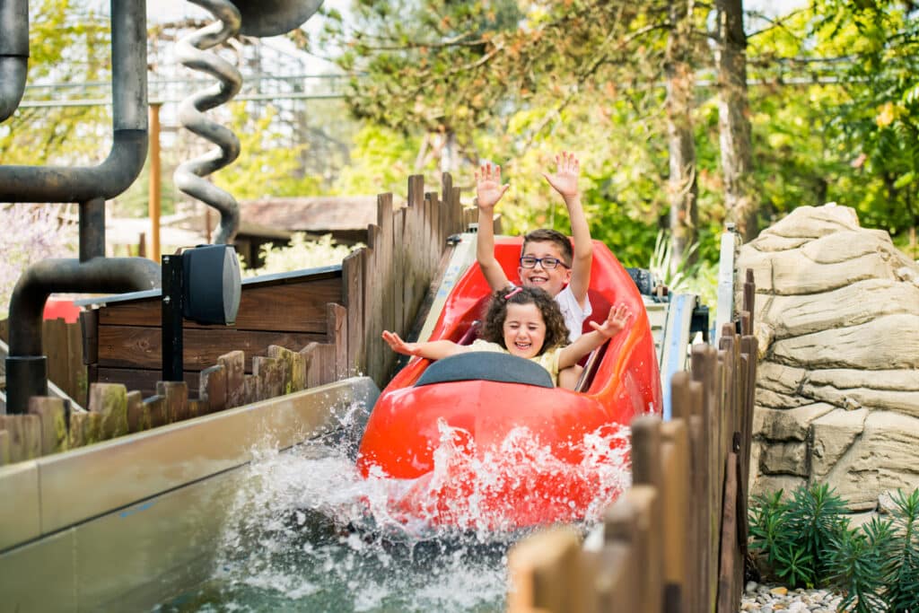 een jongetje en een meisje in een rood karretje in een waterattractie in Walibi Rhône-Alpes