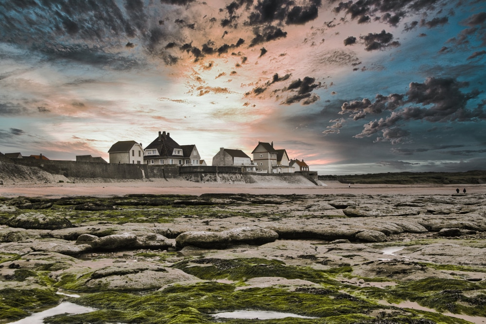 huizen aan de kust van Audreselles met een onheilspellende lucht tijdens zonsondergang